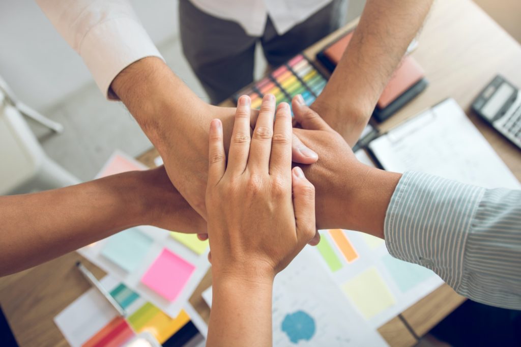 Close up of group of business people joining their hands together in unity.