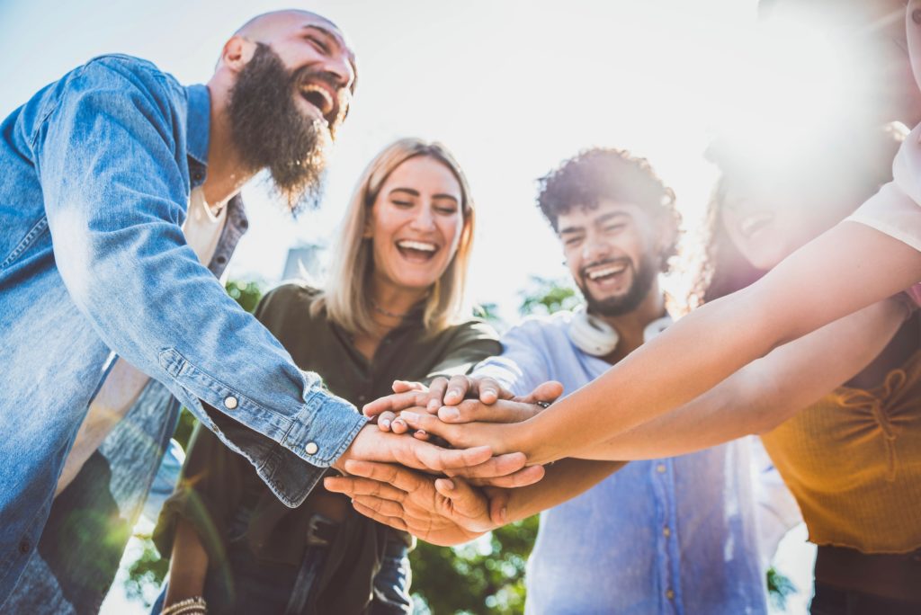 Multiracial happy young people stacking hands on top of each other